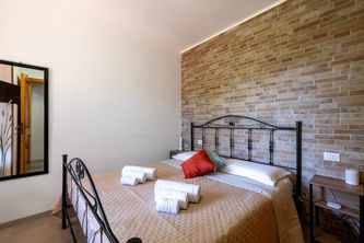Camera da letto accogliente con letto matrimoniale, muro in mattoni e specchio.