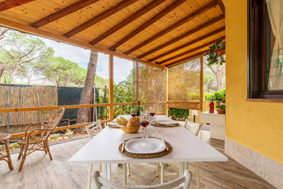 Patio coperto con tavolo apparecchiato per due, vino e pane.