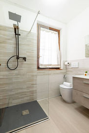 Bagno moderno e luminoso con doccia walk-in, WC e lavabo.