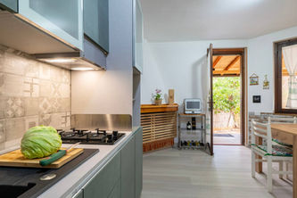 Cucina moderna con cavolo fresco sul piano cottura, porta aperta sul giardino.