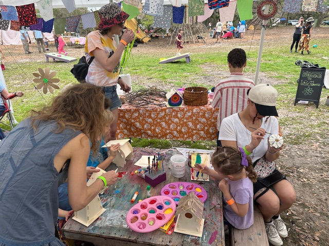 Parents & children enjoying arts and crafts in the kids area, building and painting bird houses, painting pinecone flowers, weaving