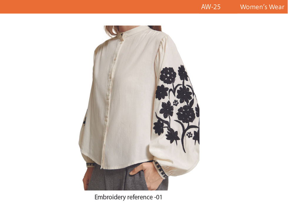 a woman wearing a white shirt with black embroidery on the sleeves