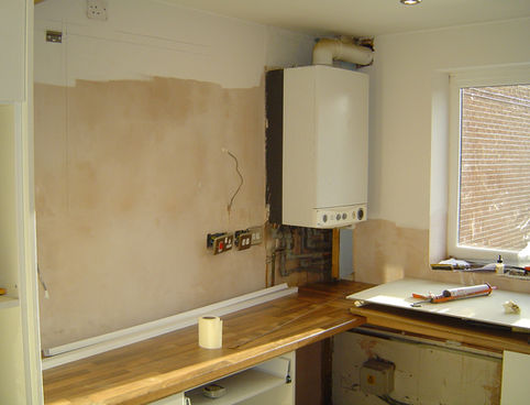 Plastered walls next to boiler above kitchen worktop