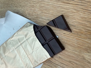 inside of open pack of dark chocolate on work desk as great afternoon healthy work snack 