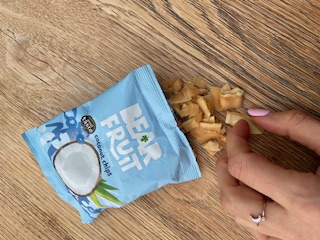 Nutritionist taking a handful of healthy coconut chips whilst working in the office 