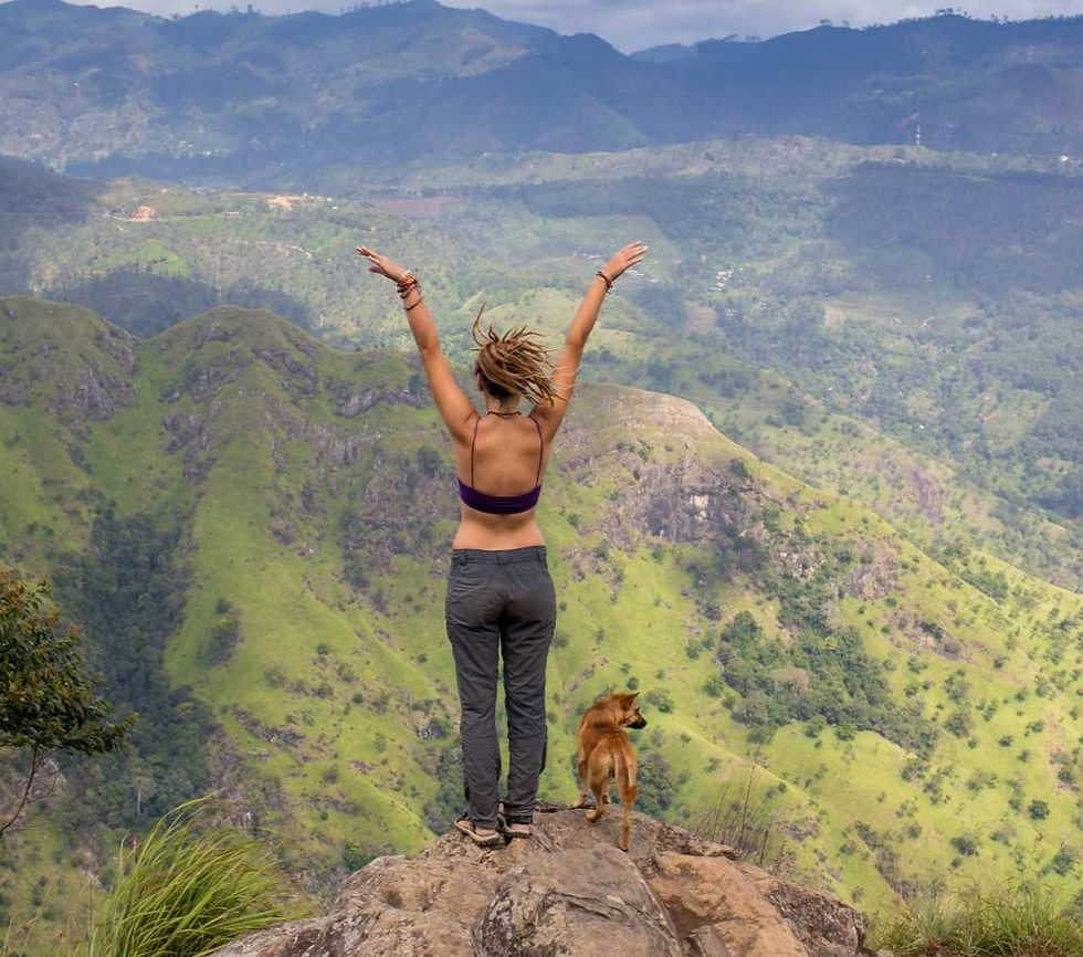 Frau auf einem Berg, die die Arme in die Luft streckt mit Hund, fit vital, glücklich