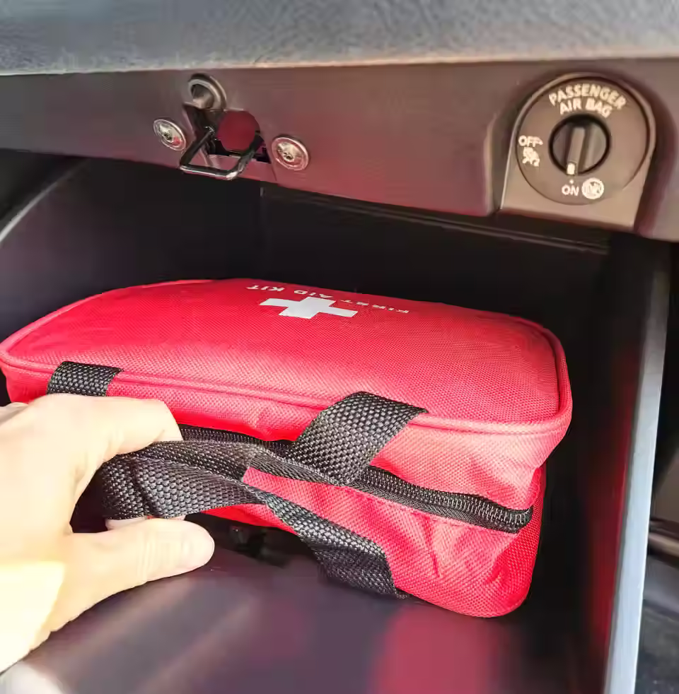 Kit d'urgence pour voiture dans sa trousse rouge placée dans la boite à gants