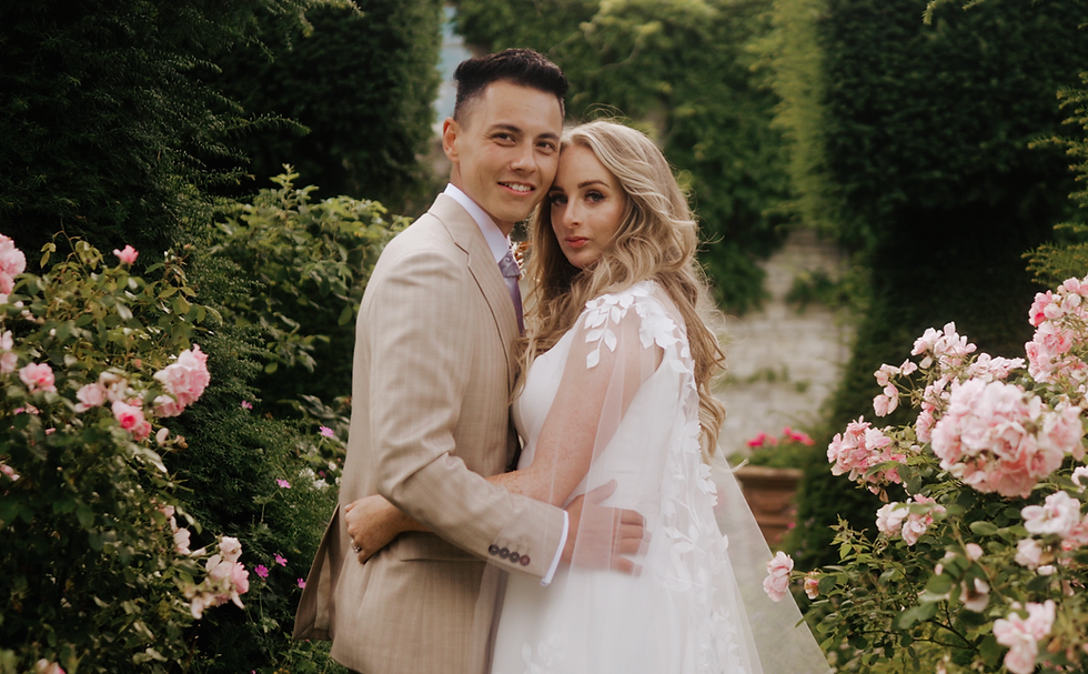 Bride and groom embrace in lush garden with pink roses at Euridge Manor with a film shoot by james freestone films
