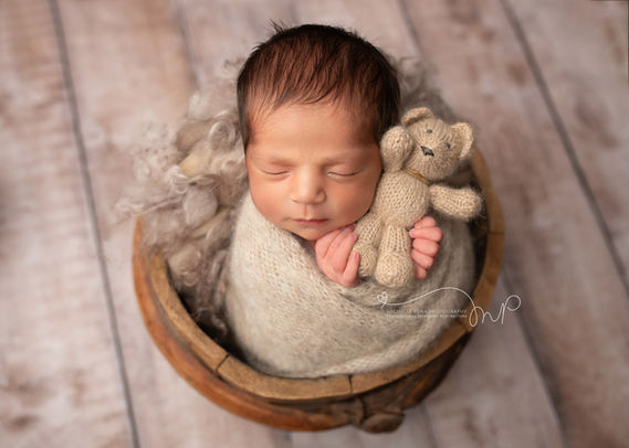 newborn baby photography  in Victoria,Texas using tan/brown colors and light wooden floor. Baby boy is holding a tan stuffed bear.