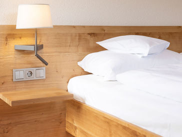 Ein sauberes Doppelzimmer mit Nachttisch, Lampe und Steckdose, Adler Glottertal.
