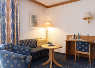 Gemütliches Hotelzimmer mit Sofa, Tisch und Lampe; Adler Glottertal im Hintergrund.