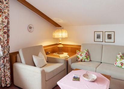 Gemütliche Sitzecke mit Sofa, Sessel, Tisch und Lampe; Adler Glottertal im Hintergrund.