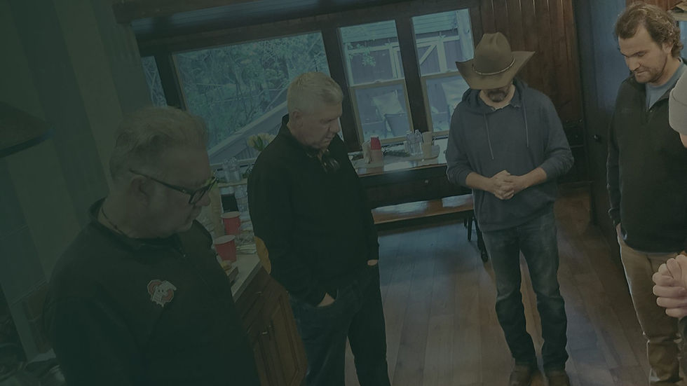 Men gathered in a wood-panelled cabin living room during an evening retreat session