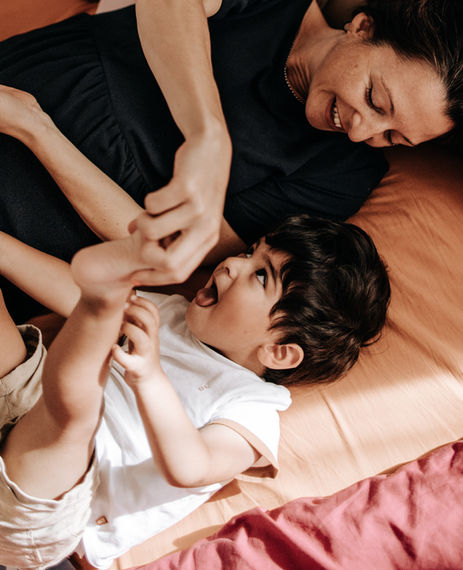 shooting photo famille -une mère et son bébé chahutant sur le lit