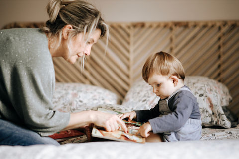 shooting photo famille -une mère et son bébé lisant une histoire sur le lit