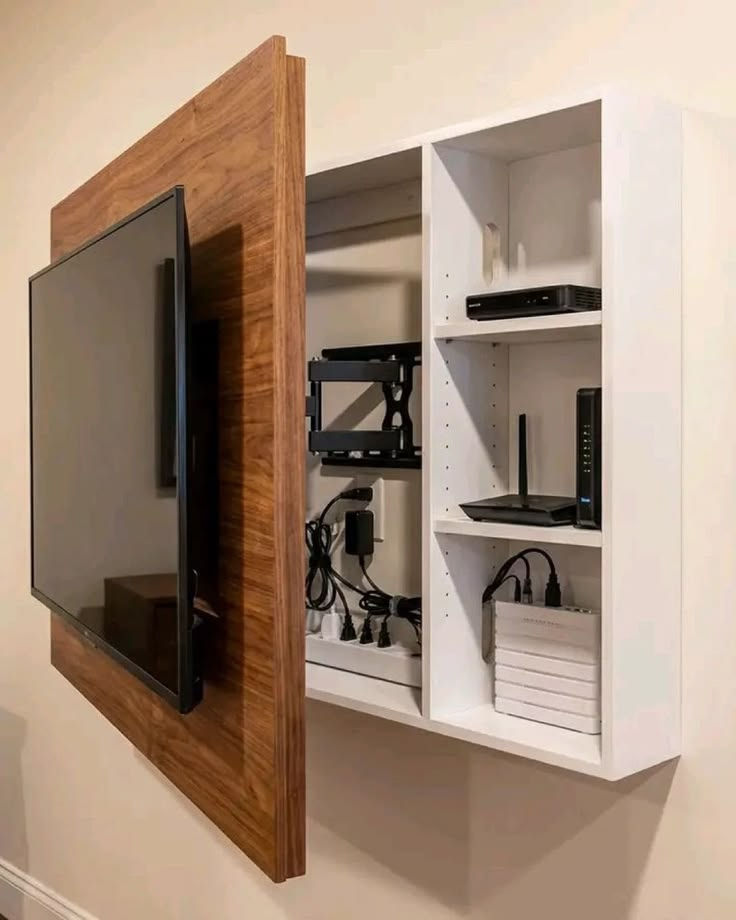 Wall-mounted TV cabinet opens to reveal routers, cables, and devices in white shelves and wood panel.