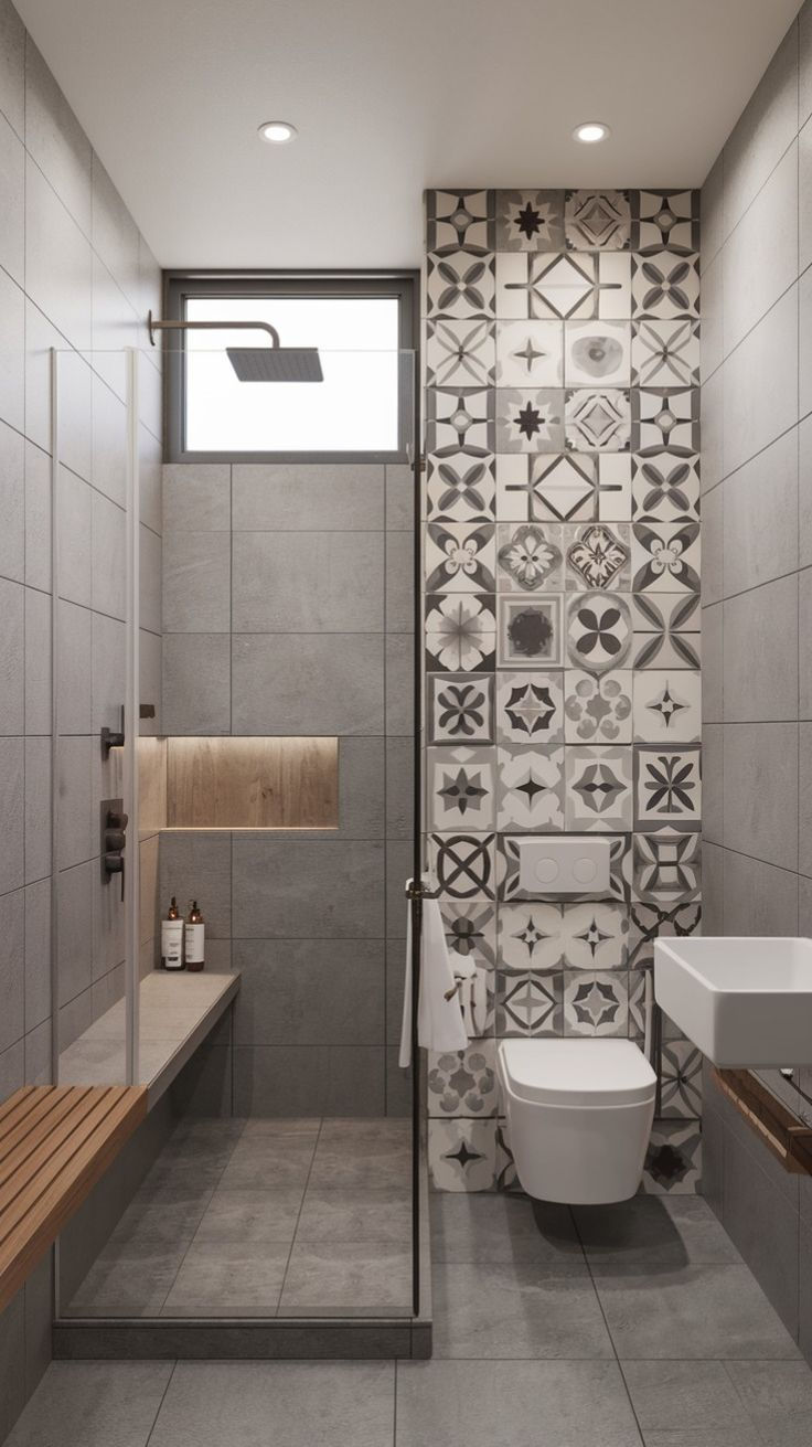 Modern gray bathroom with shower, wall-mounted toilet, and patterned tile accent wall beside a white sink and bench.