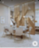 Elegant modern dining room with white chairs, marble floor, wooden slat divider, and glowing pendant lights in a calm neutral space