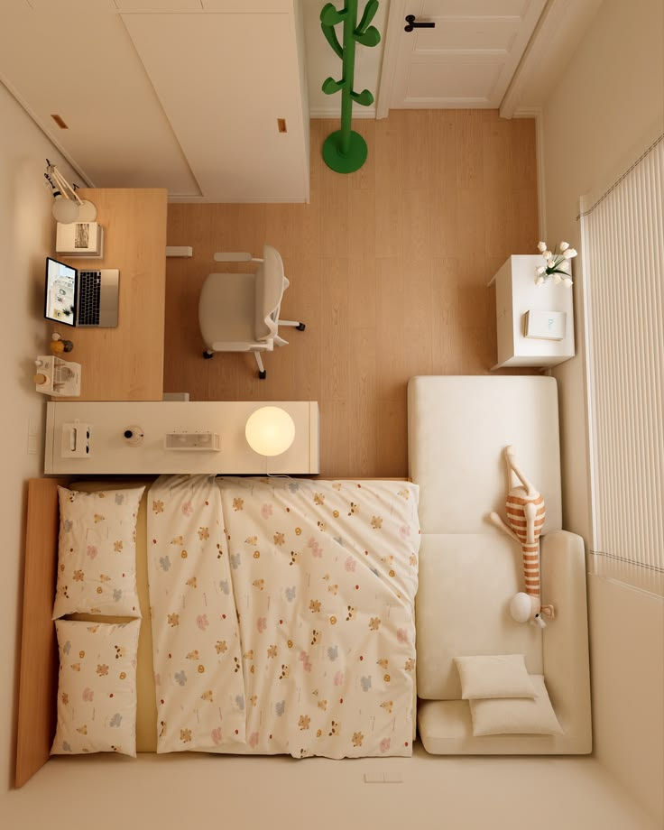 Top-down view of a cozy bedroom-office with a bed, desk with laptop, white sofa, and green coat rack in a beige room.