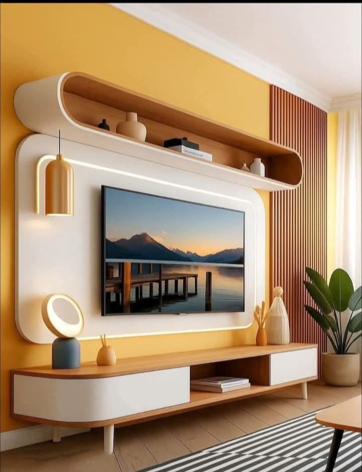 Modern living room with mustard walls, wall-mounted TV showing a sunset lake, shelves, decor, striped rug, and a potted plant.