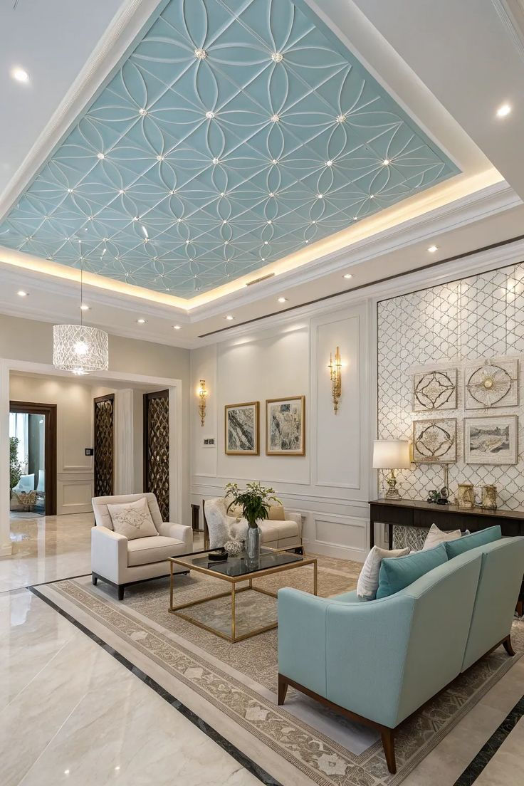 Luxurious living room with aqua patterned ceiling, white and blue chairs, gold accents, wall art, and a glass coffee table.