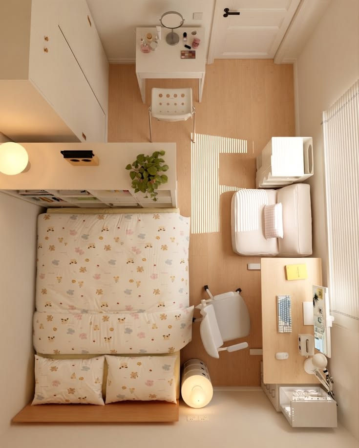 Sunlit top-down view of a tidy bedroom-office with floral bed, desk, chair, sofa, plant, and striped window light.