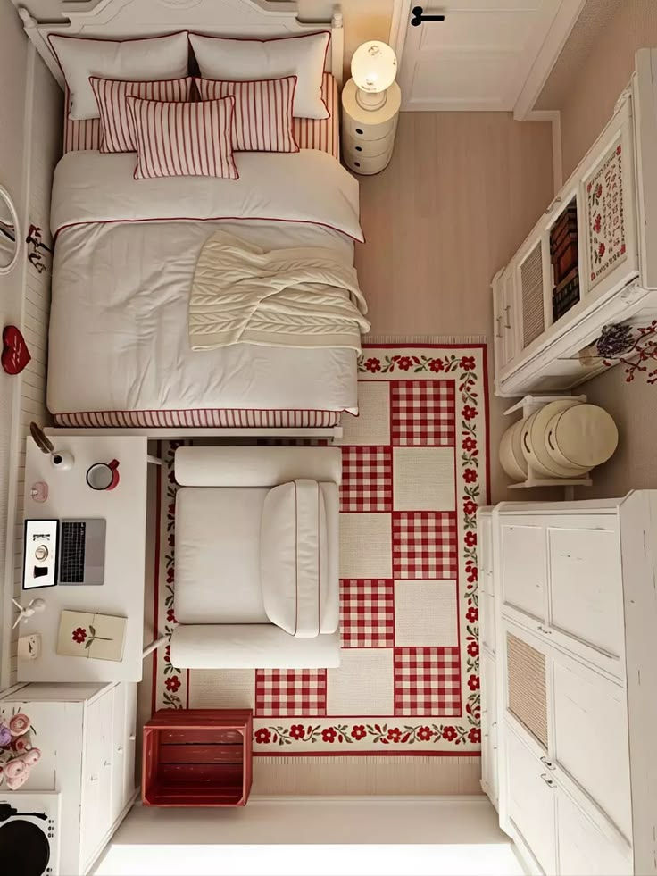 Cozy top-down bedroom with a bed, white armchair, red-and-white checkered floral rug, desk, and soft neutral decor.