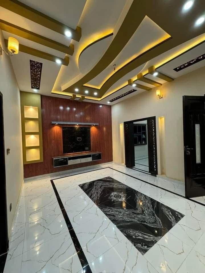 Modern empty living room with glossy marble floor, wood media wall, gold-lit ceiling, and black doors.