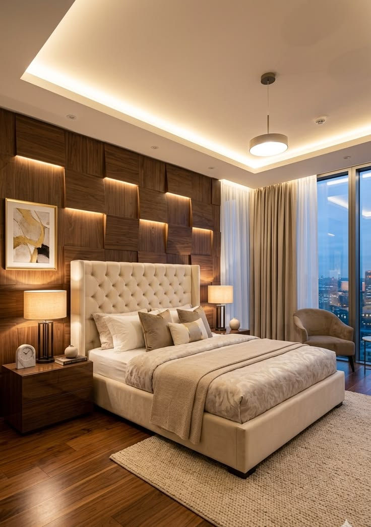 Cozy modern bedroom with tufted bed, warm wood accent wall, lamps, and a city view through tall windows at night.