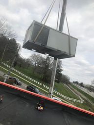 A crane raising a new air conditioning unit to be installed by Buckeye Mechanical