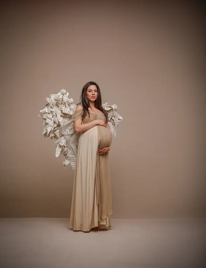 Babybauch Fotograf Berlin – werdende Mutter in beigem Kleid mit weißen Blumen, Studio Lesemann