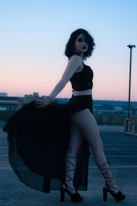 Woman in black dress poses, evening skyline background, fashionable look, elegant pose