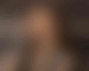 Woman posing thoughtfully under warm studio lighting.