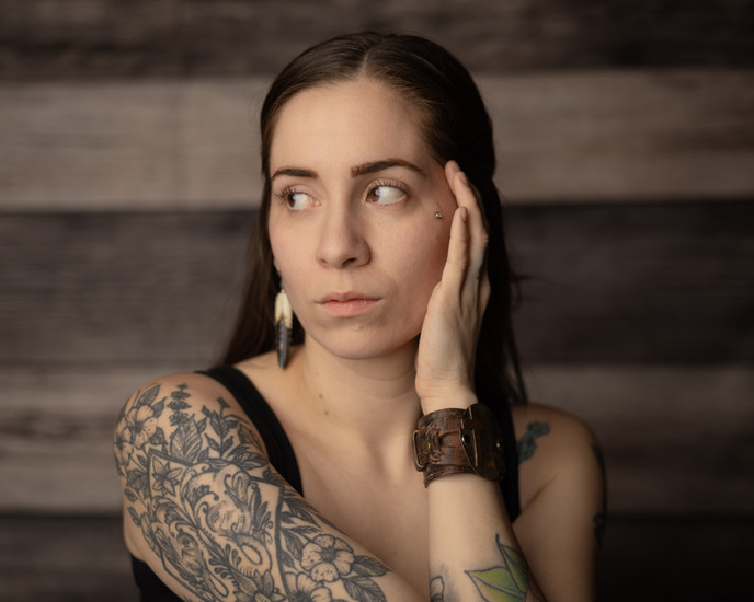 Woman seated in studio lighting, contemplating the journey through the lens.