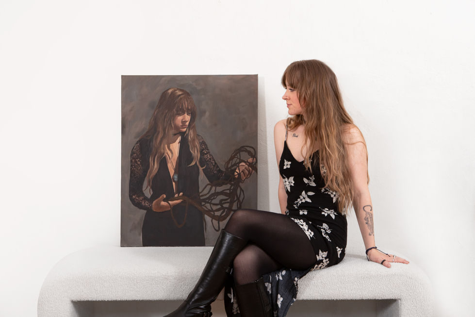 a woman with a tattoo on her arm sits next to a painting of a woman holding a whip