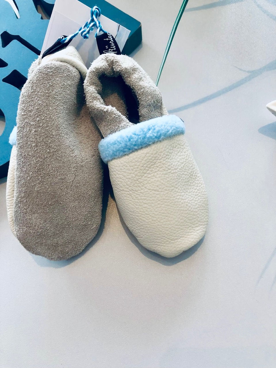 Miniaturbild: Weiche Baby-Krabbelschuhe aus weißem Leder mit hellblauer Umrandung und Fleece-Futter, handgefertigt und personalisierbar.