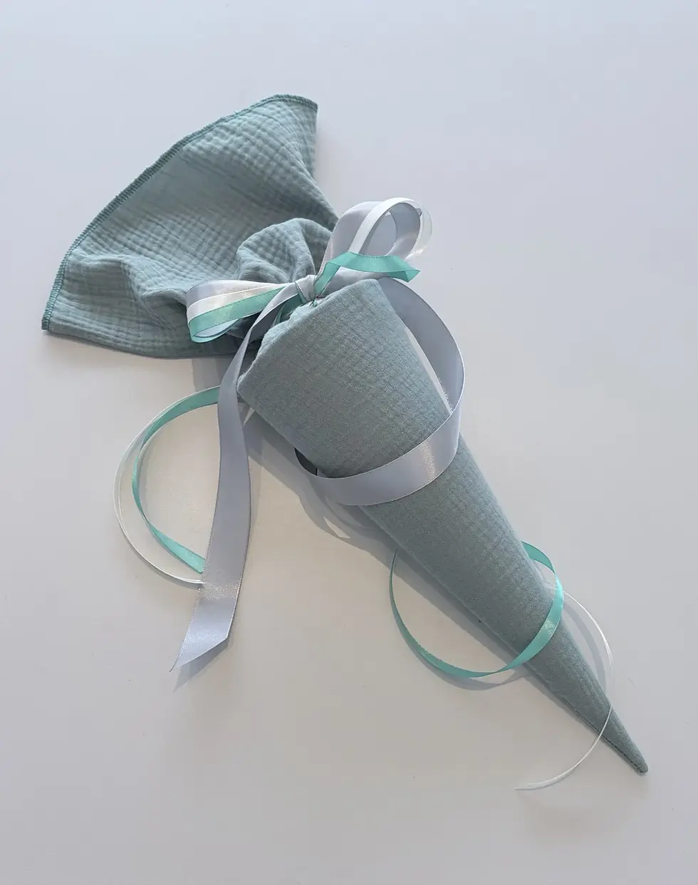 Miniaturbild: Personalisierte Musselin Schultüte in Türkis mit weißen und mintfarbenen Satinbändern für den Übertritt auf das Gymnasium.