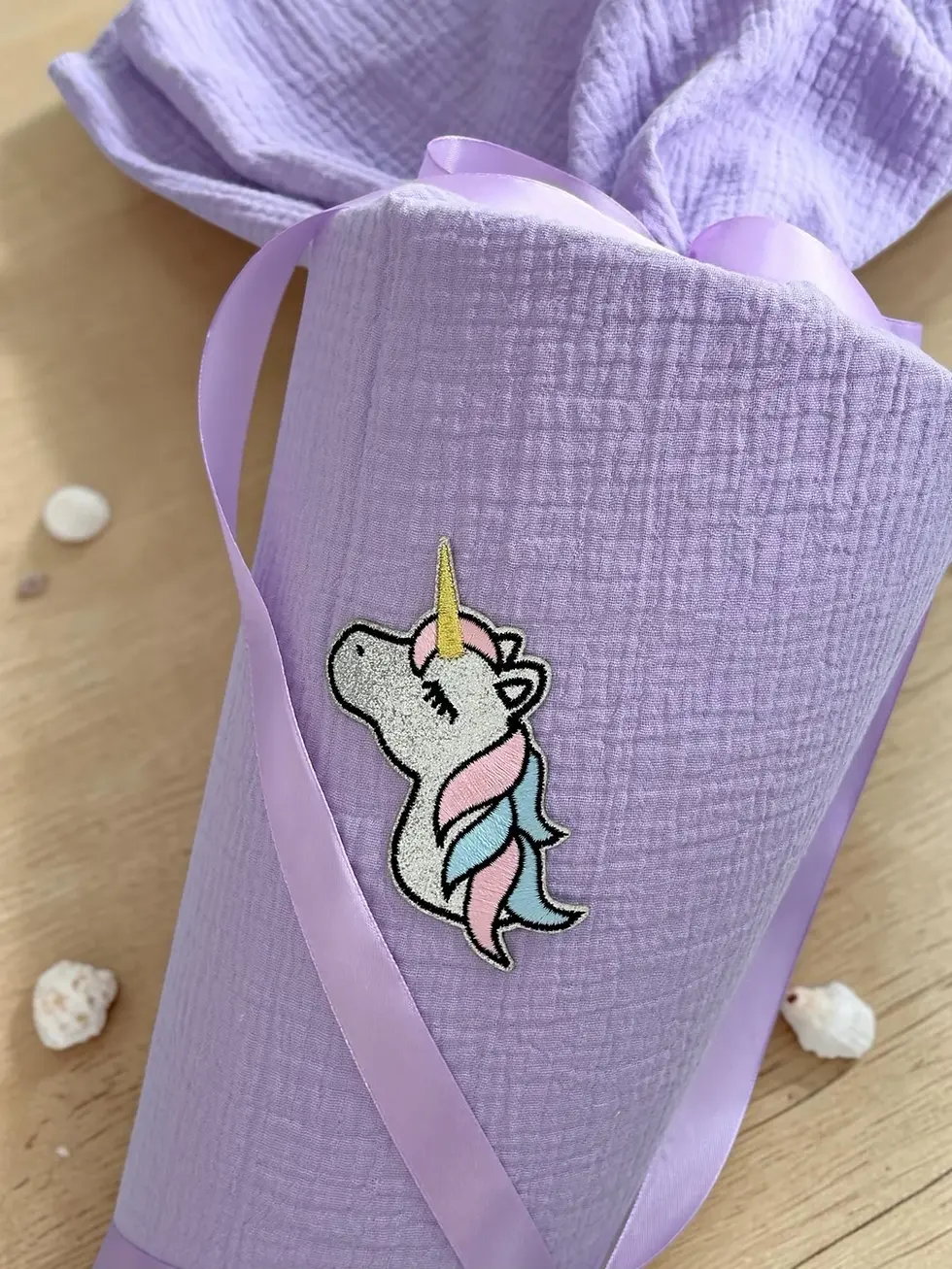 Miniaturbild: Detailansicht der Einhorn-Applikation auf einer fliederfarbenen Musselin Schultüte mit weicher Musselinstruktur.