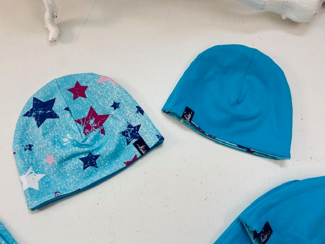 Miniaturbild: Niedliche Wendemütze für Babys und Kinder in türkis mit bunten Sternen, eine Mütze zwei Looks.