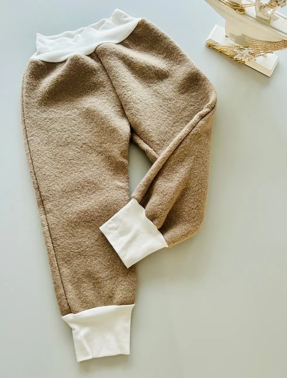 Miniaturbild: Beige Walkhose für Babys und Kinder im Flatlay, mit cremefarbenem Bauchbund und Beinbündchen, handgefertigt aus Wolle