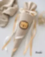 Beige Kindergartenschultüte aus Musselin mit Löwen-Applikation und cremefarbenen Schleifen. Personalisierbare Geschwistertüte