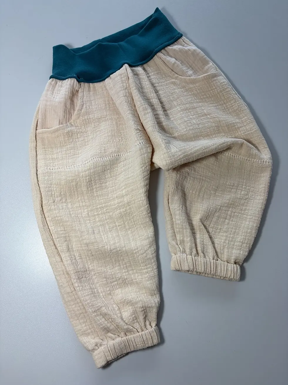 Miniaturbild: Handgemachte Musselinhose Janni in Beige mit feinen Ziernähten und Taschen, weich zur Kinderhaut und angenehm luftig.
