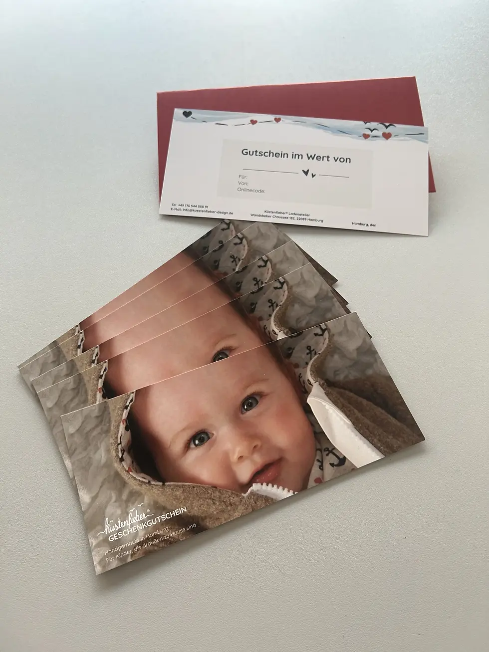 Miniaturbild: Nahaufnahme eines Küstenfieber® Geschenkgutscheins mit Babybild. Emotionales Geschenk für Geburt, Taufe oder Geburtstag.