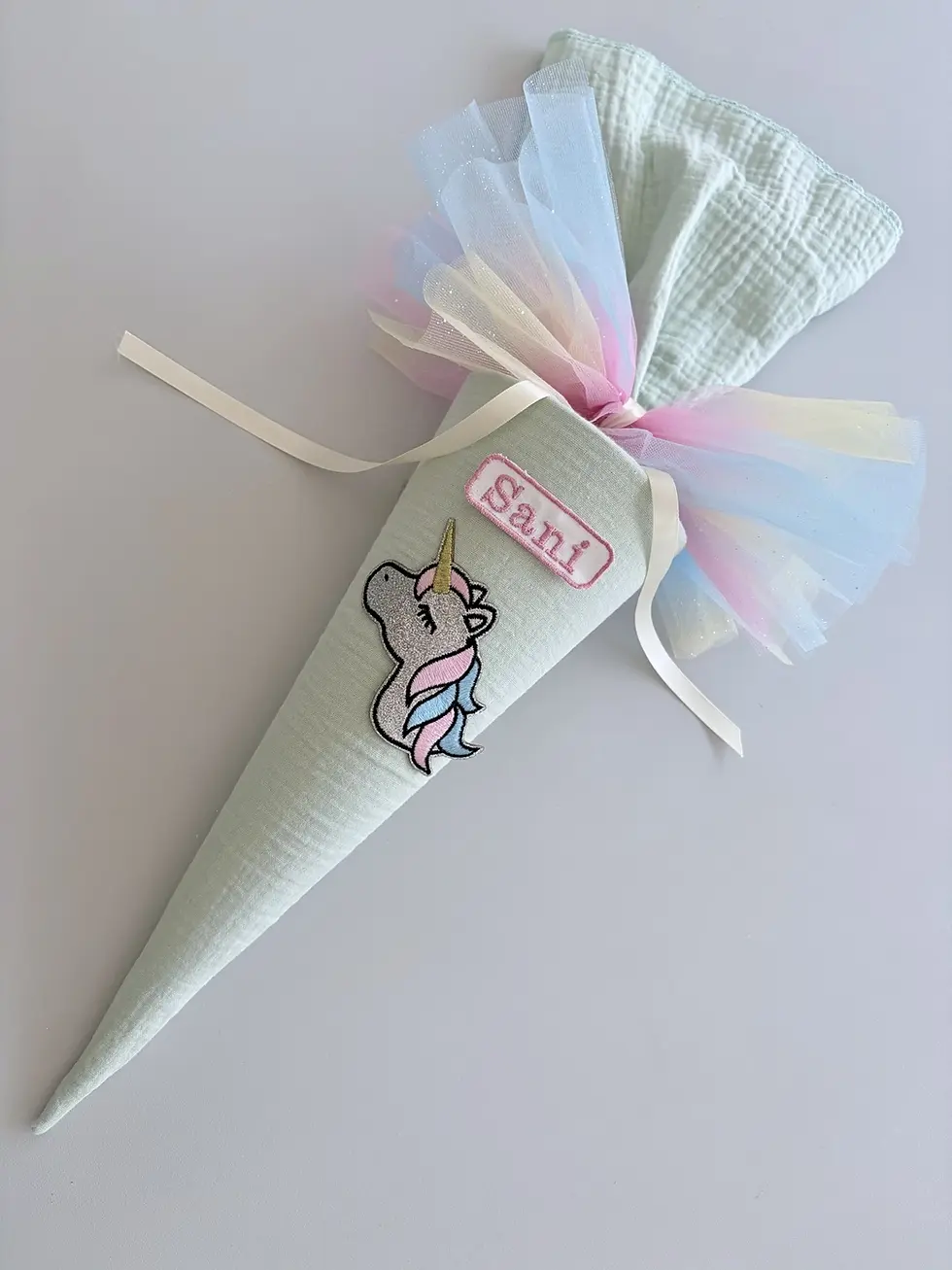 Personalisierte kleine Musselin Schultüte in Mint mit Einhorn-Applikation, Namenspatch und schimmernder Regenbogen-Tüll.
