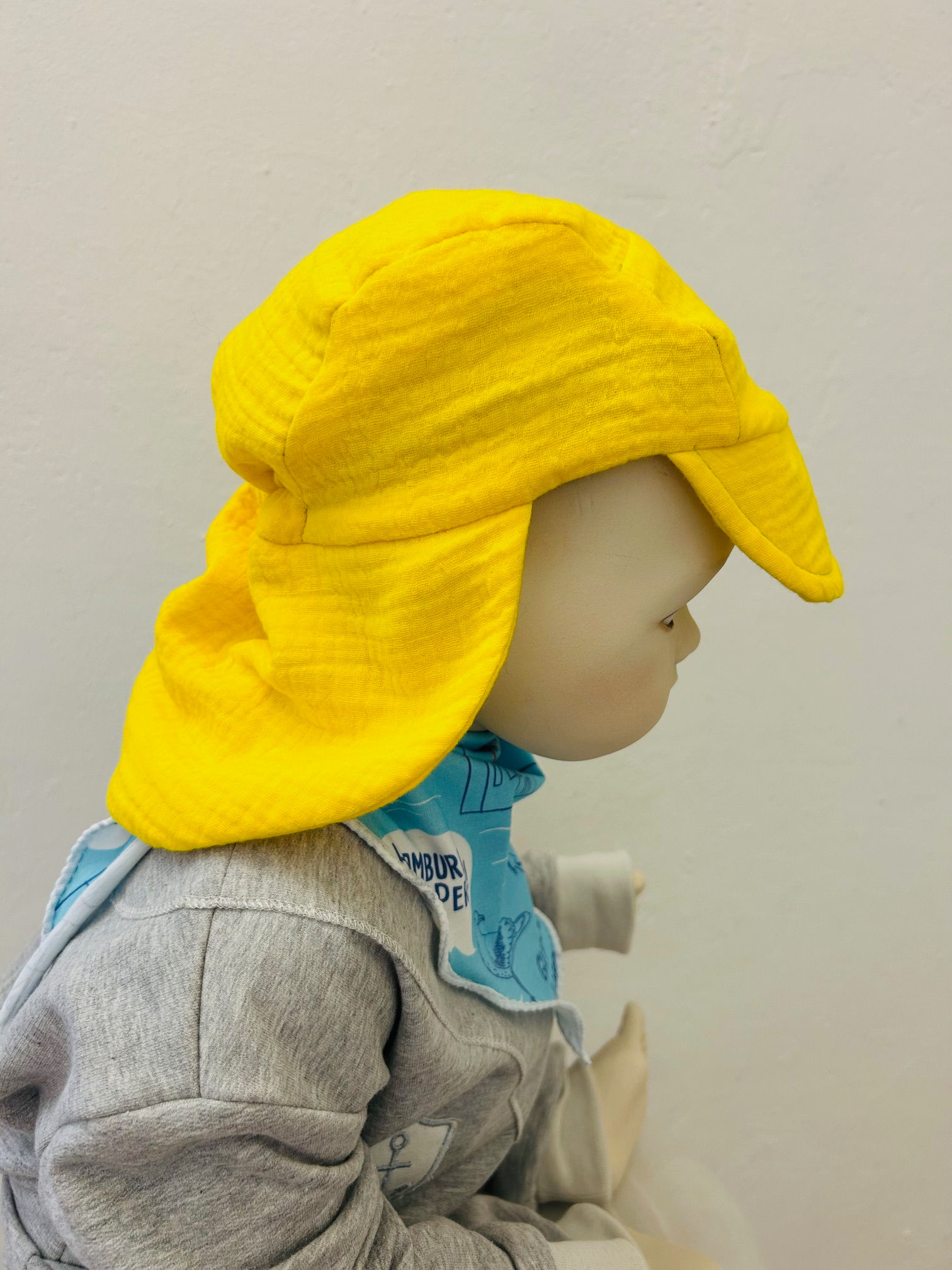 Zitronengelbes Musselin Sommer Cap mit Nackenschutz für Babys und Kleinkinder, ideal für sonnige Tage.