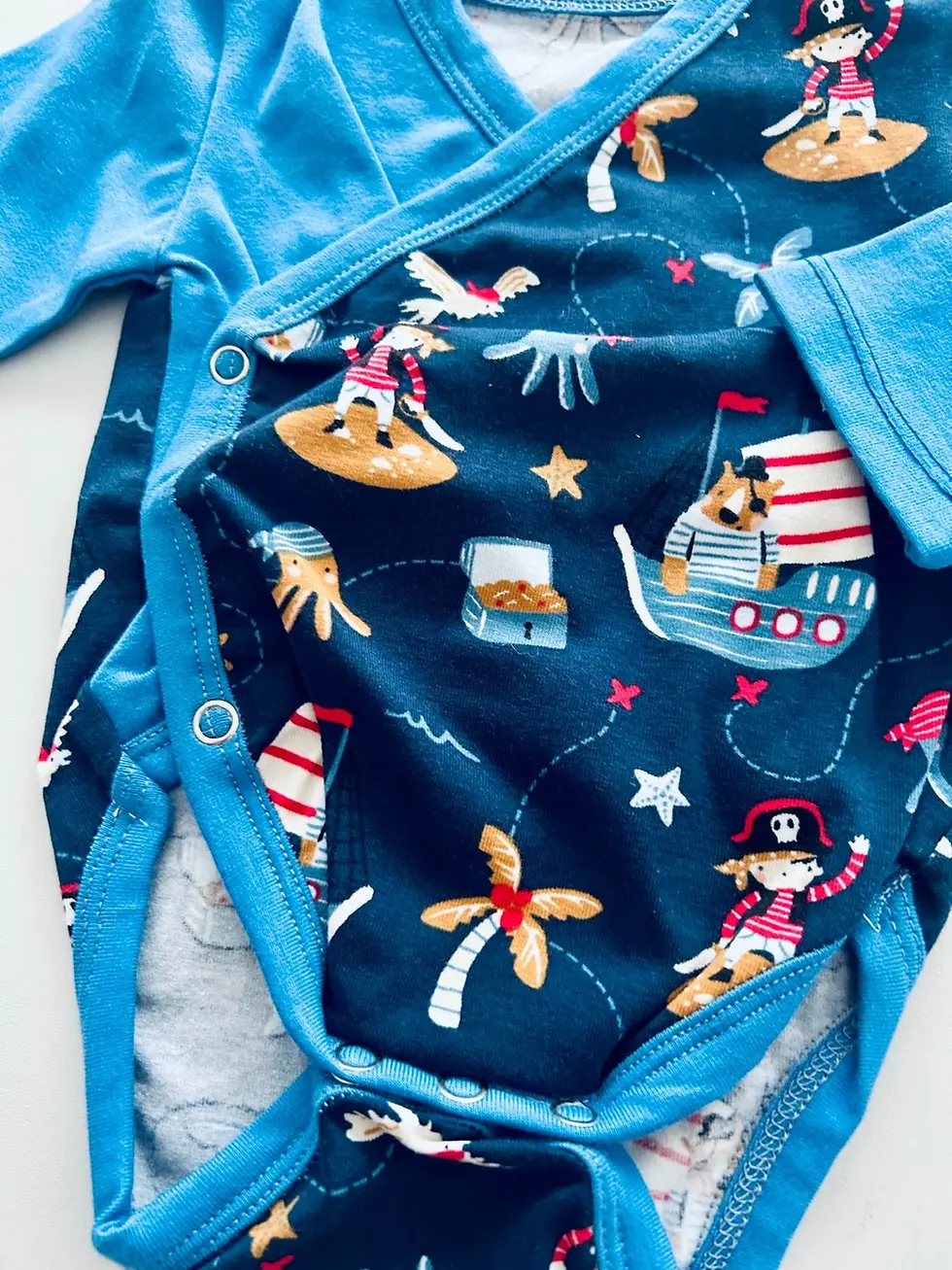 Miniaturbild: Wickelbody für Babys mit Seeräuber-/Piratenprint, langarm in Ozeanblau, leicht anzuziehen – handgemacht in Hamburg von Küsten
