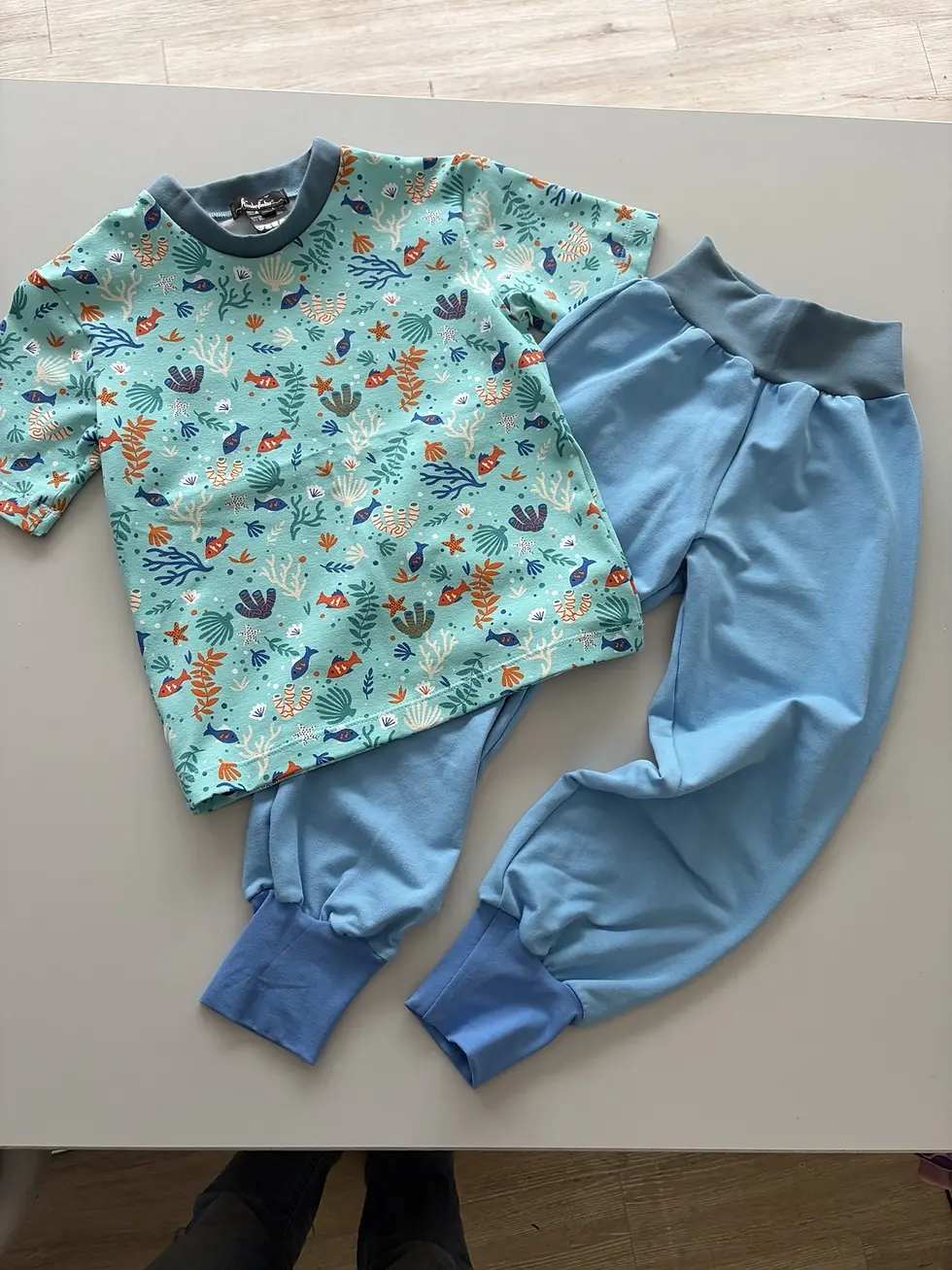 Miniaturbild: Kind entspannt mit Buch im maritimen Shirt mit Unterwasser Motiven, weicher Baumwollstoff OEKO-TEX, handgemacht in Hamburg