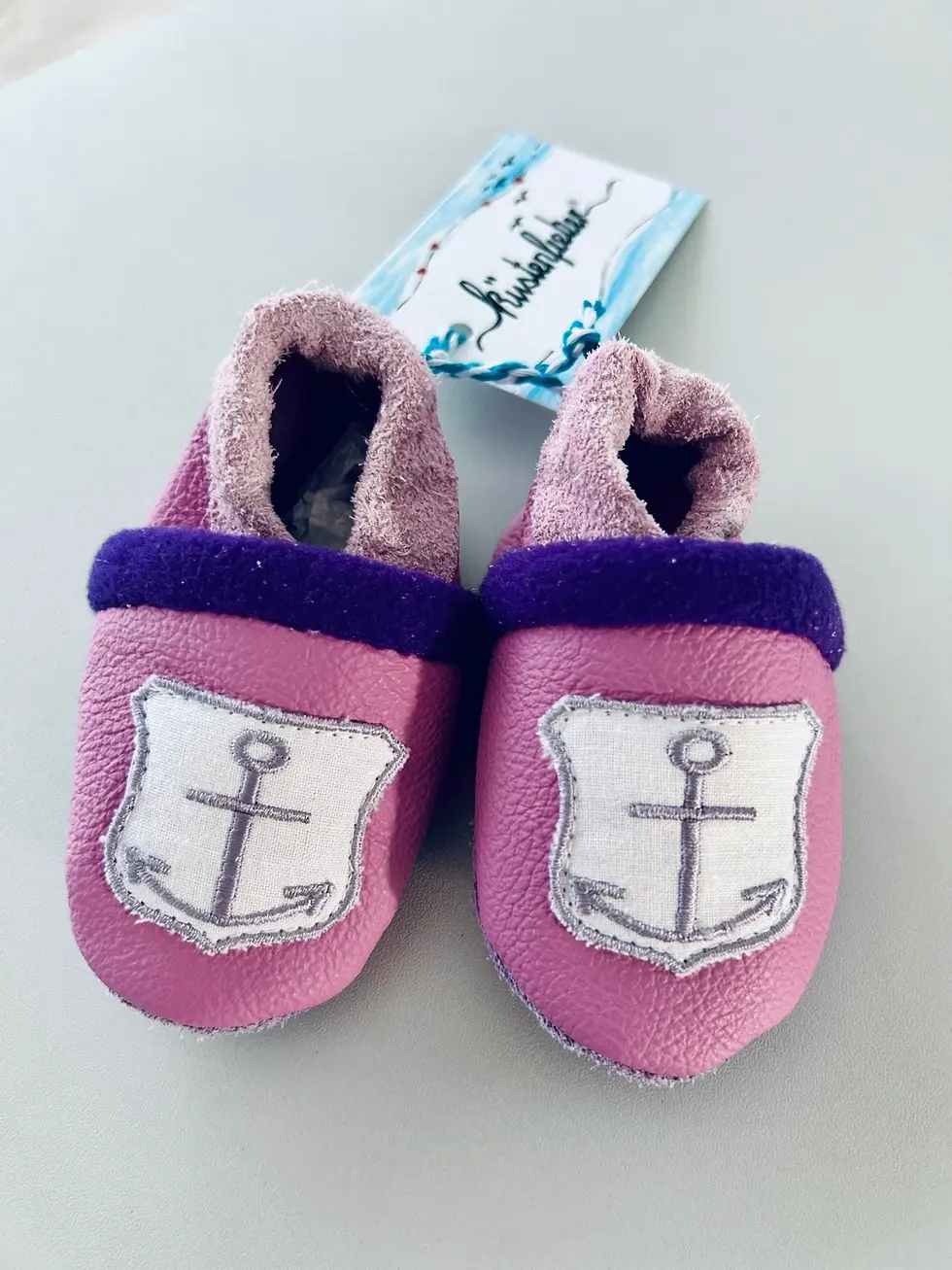 Miniaturbild: Handgemachte rosa Lederpuschen für Babys mit Anker-Patch und weichem Futter. Rutschfest, bequem und ideal für warme Füßchen i