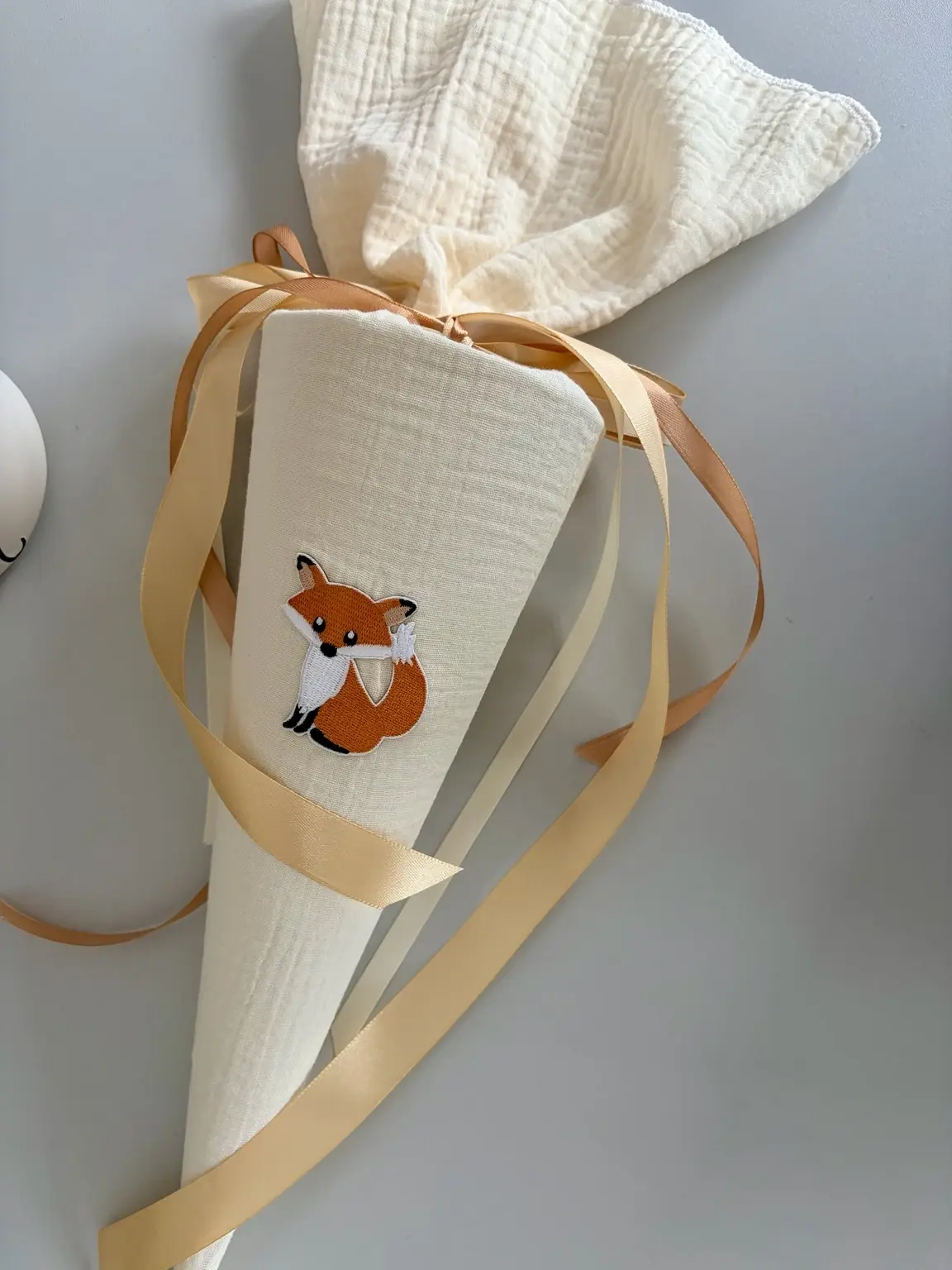 Kleine Musselin Schultüte „Kleiner Fuchs“ aus cremefarbenem Double Gauze mit niedlicher Fuchs-Applikation und Satinbändern.