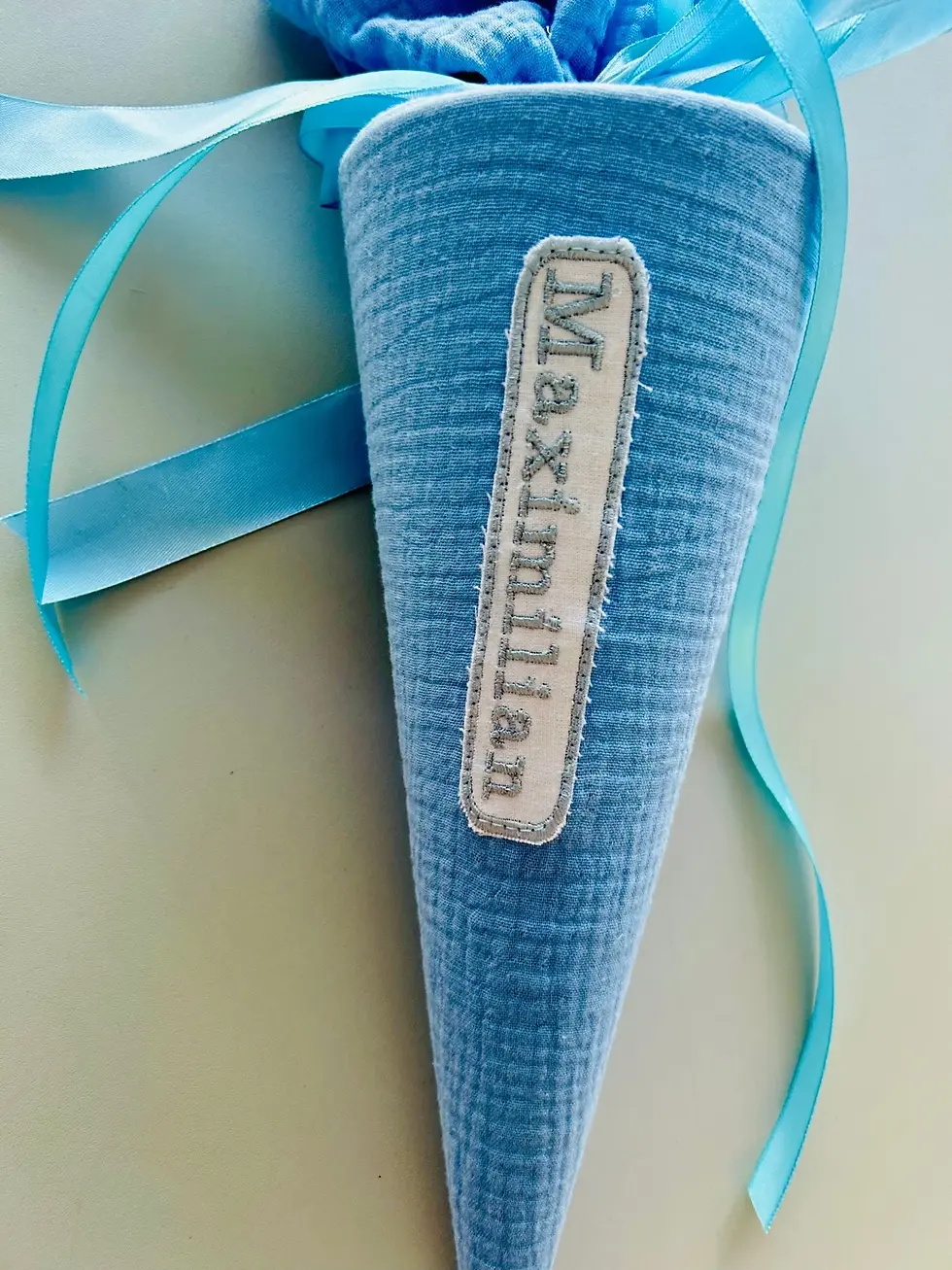 Miniaturbild: Detailaufnahme der handgemachten Musselin-Schultüte in Hellblau – liebevoll genäht, mit stabiler Papprohling-Einlage.